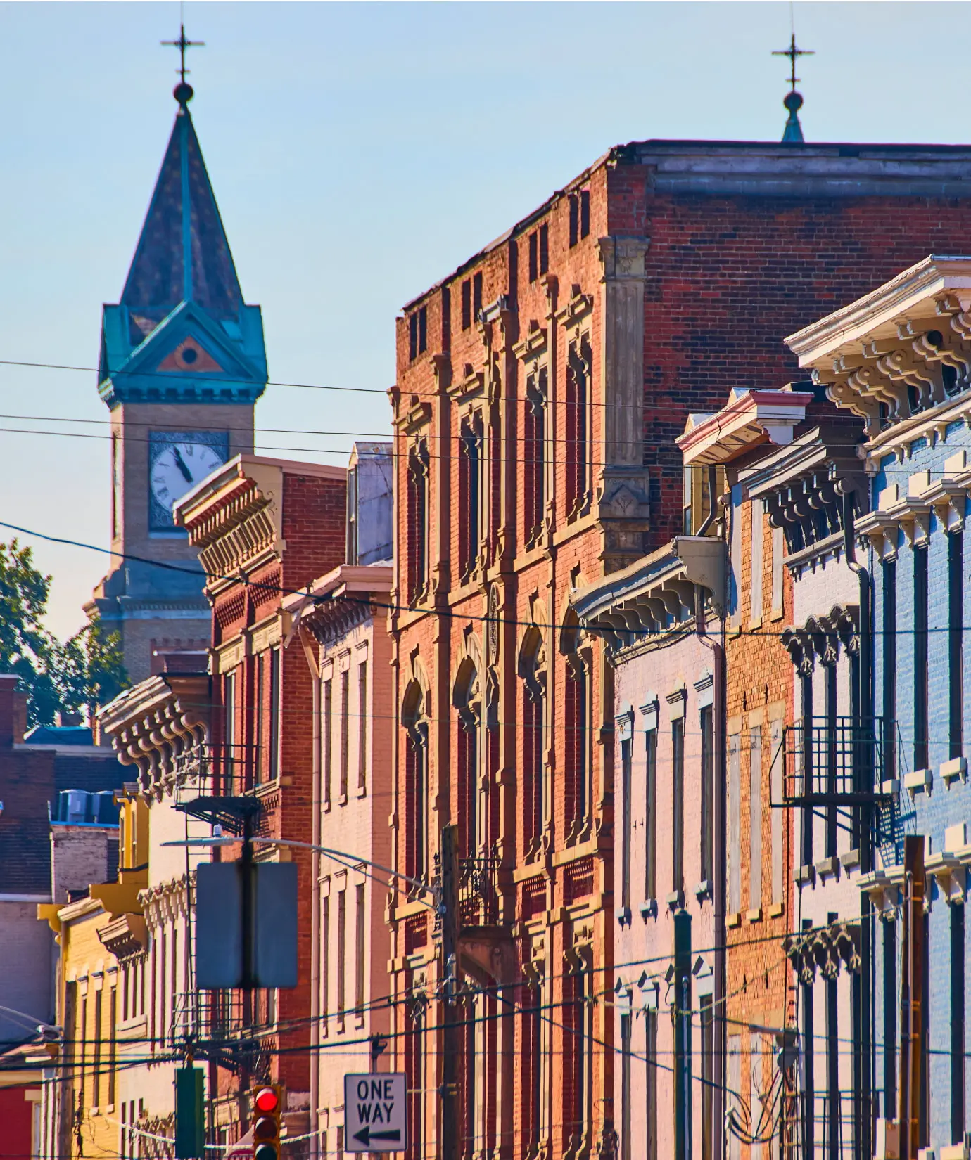 A row of colorful historic brick buildings lines a city street with a clock tower visible in the background.