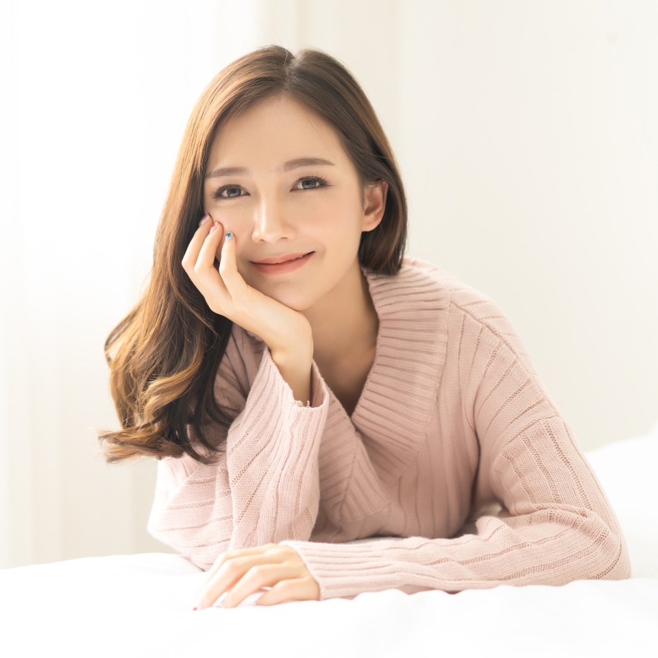 Portrait of young Asian woman smiling friendly and looking at camera in living room.Woman's face closeup. Concept woman lifestyle and winter. Autumn, winter season.