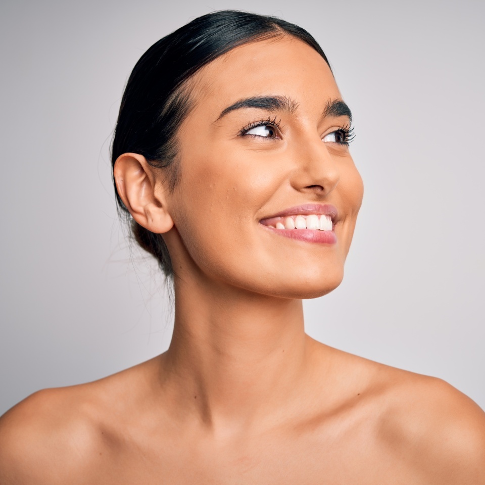 Close up of young beautiful woman with clear and pure skin. Perfect and clean skincare wearing natural makeup. Smiling happy looking fresh and healthy.