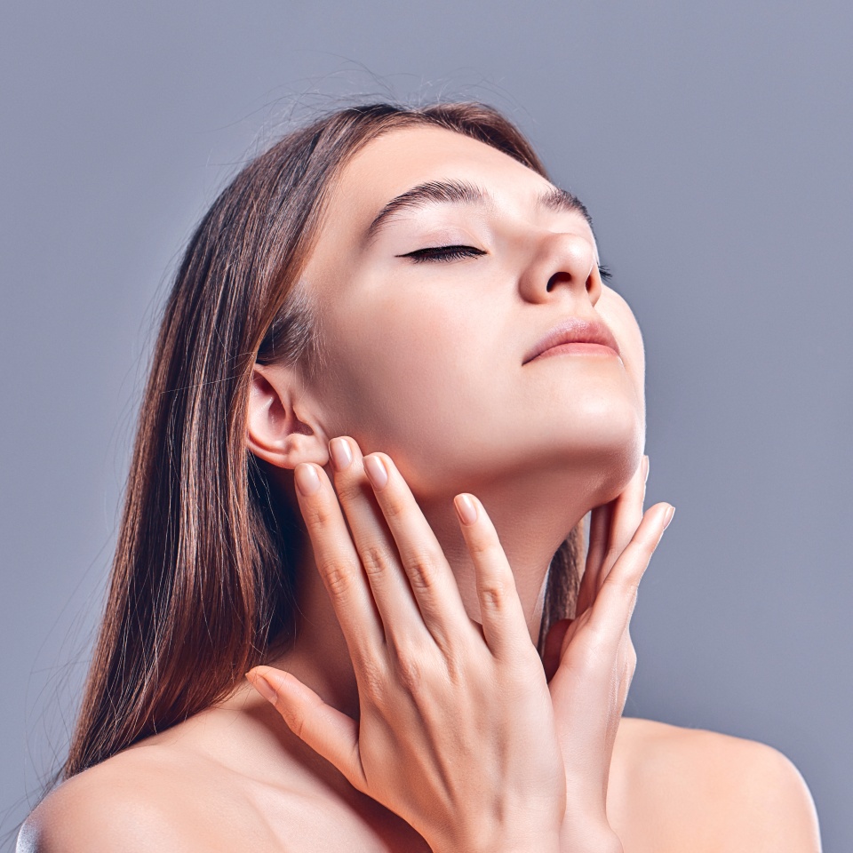 Beautiful young woman with clean perfect skin. Portrait of beauty model with natural nude makeup. Spa, skin care and wellness. Close up, gray background, copyspace.