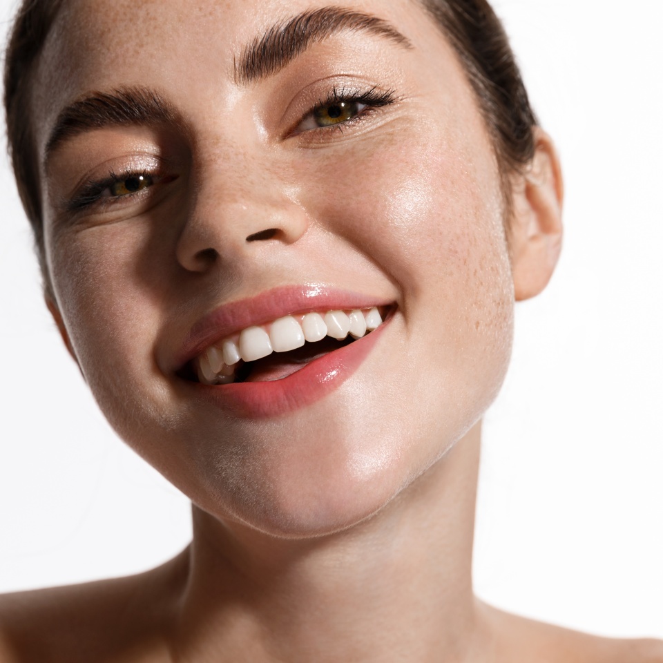 Beauty face of woman touch clean and fresh hydrated skin, perfect facial nude makeup and smile, standing naked shoulders. Girl advertising cosmetics with spf sun protecting, botanical ingredients