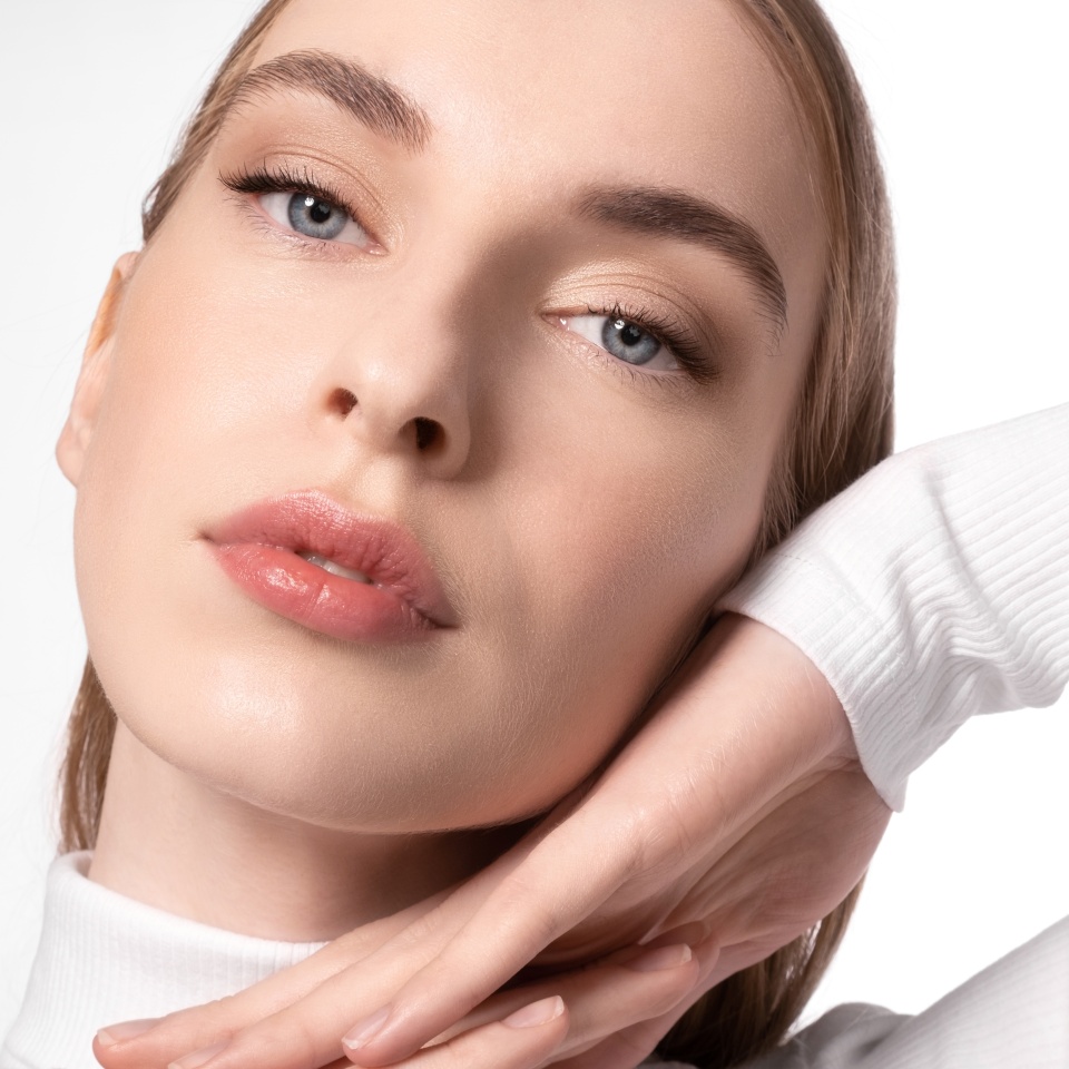 Close-up of a tender young woman with perfect soft skin with natural makeup on a white background.