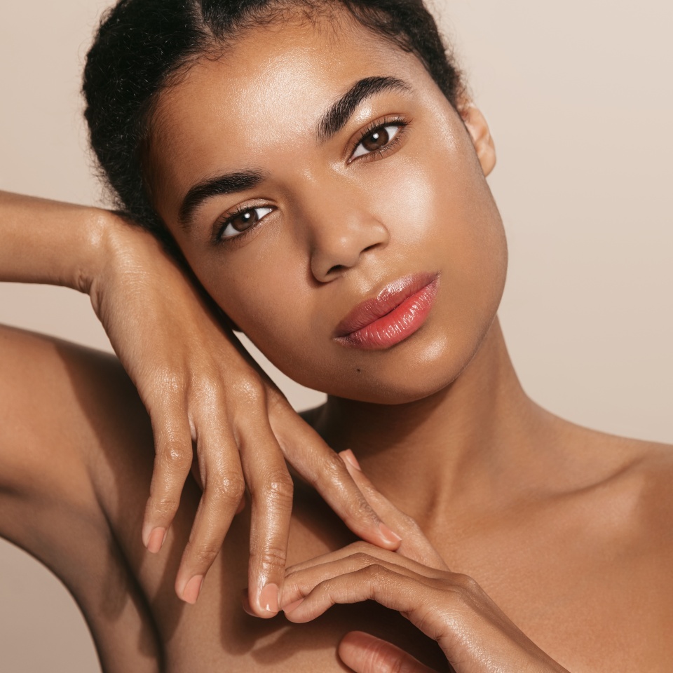 Spa and cosmetics. Young black woman with glowing, clean and natural skin, posing with bare shoulders, face after cleansing gel and skincare routine, standing over brown background.