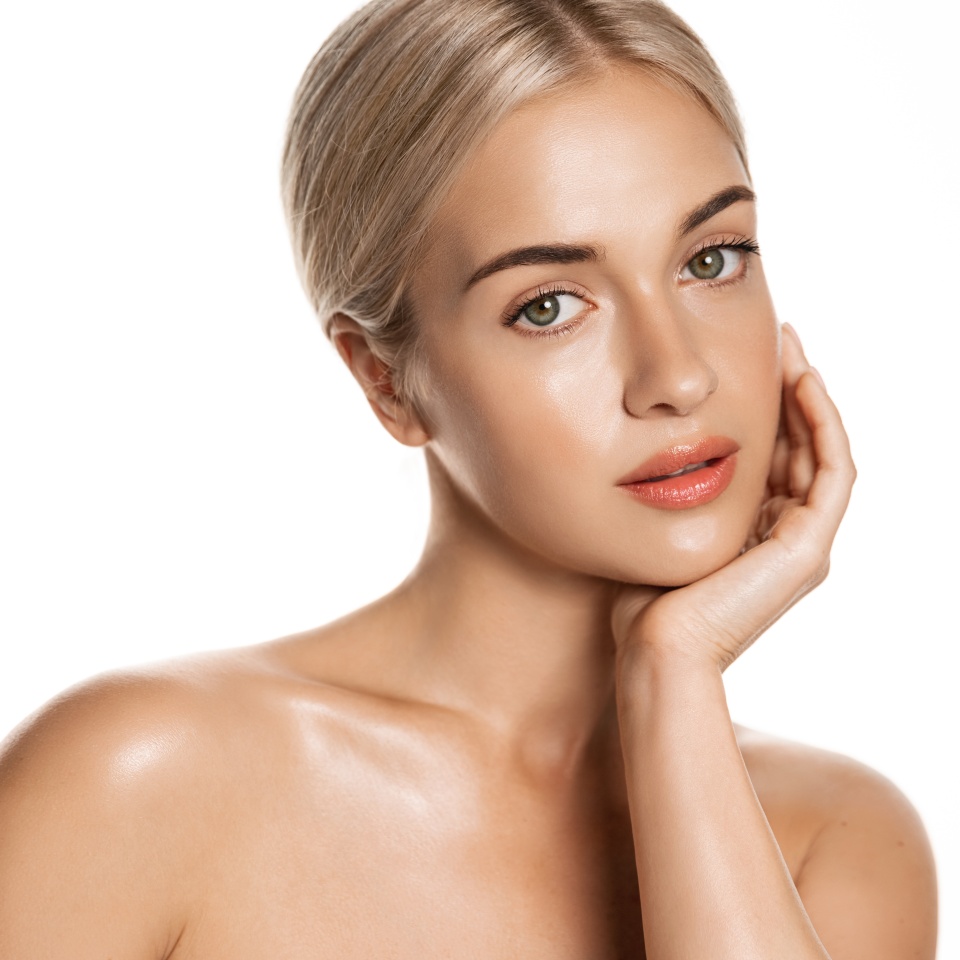 Beauty skin. Head and shoulders of blond woman model, touching glowing, hydrated facial skin, apply toner, skin cream or lotion for healthy look, after shower portrait, white background.