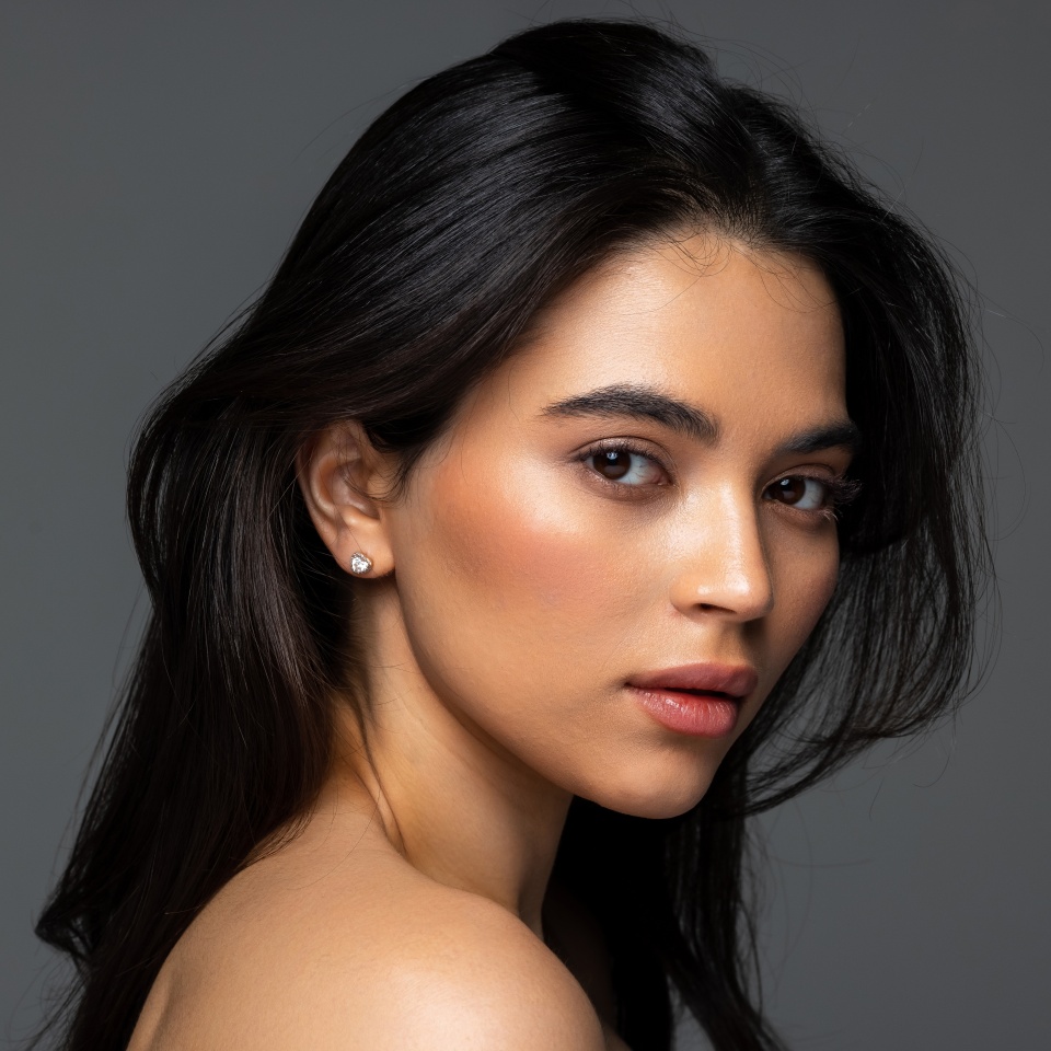 Close up beauty portrait of a laughing beautiful half naked woman applying face cream and looking away isolated over white background
