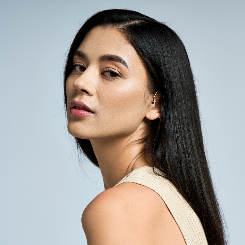 A young woman with long black hair poses against a gray background.