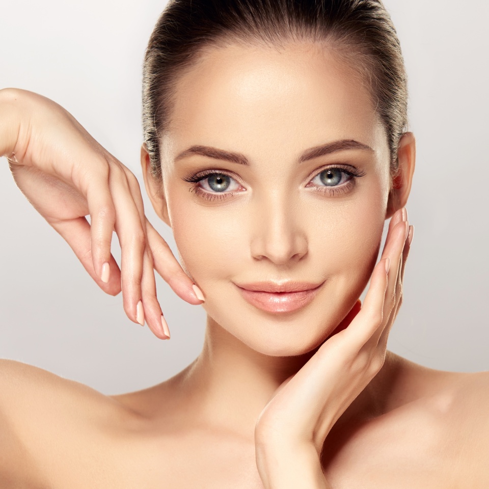 Beautiful young woman with clean fresh skin on face . Girl facial treatment . Cosmetology , beauty and spa .