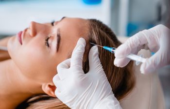 Young woman with hair problem receiving injection in clinic. Hair renewal rejuvenation pampering procedure. Cosmetology, follicles growing, botulinum treatment